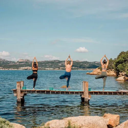 Group yoga session at 7Pines Resort Sardinia overlooking the Mediterranean