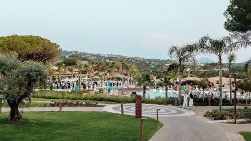 Guests enjoying an outdoor event near a pool at 7Pines Resort Sardinia, Italy