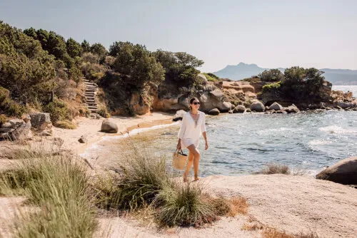 Woman enjoying a walk on the beach at 7Pines Resort Sardinia