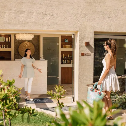 Donna in abito bianco al 7Pines Resort Sardinia, simbolo di relax e benessere tra lussureggianti verdi.