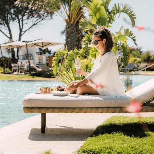 Frau genießt ihre Zeit auf einem Liegestuhl am Pool bei 7Pines Resort Sardinien.