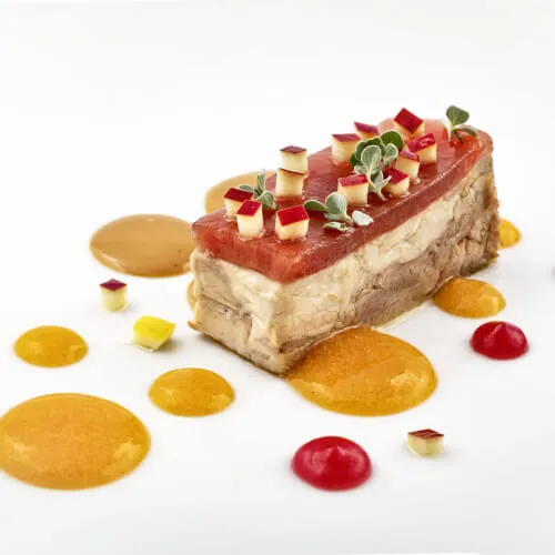 Exquisites Kuchenstück mit Fruchtgarnitur im 7Pines Resort Sardinien, präsentiert kulinarische Kunst auf einem Teller.
